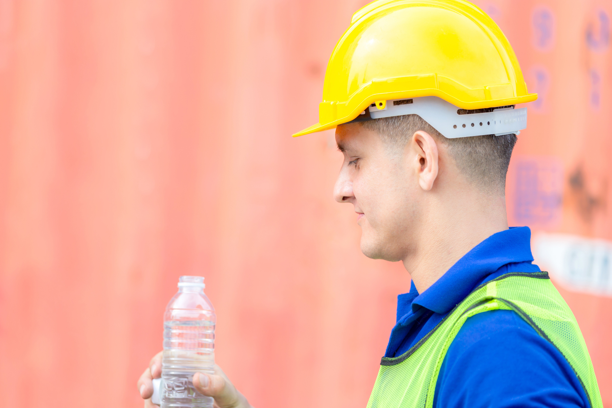 Close up of Worker man in hard hat drinking water at containers cargo Homme entrain de faire une pose lors de travaux par forte chaleur